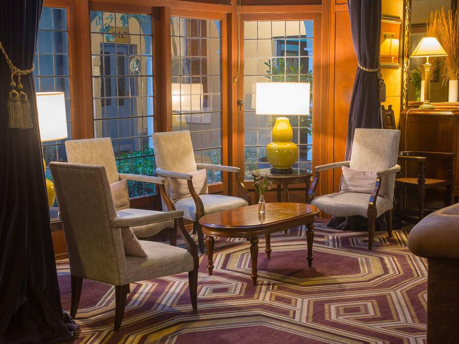 A room with four upholstered chairs, a wooden coffee table, a patterned rug, and a large window with a view.