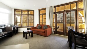 A modern living room with a sofa, television, and large windows.