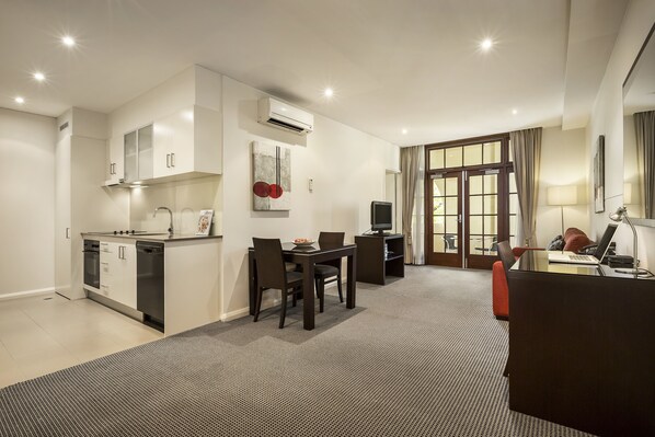 Una habitación de hotel moderna con kitchenette, comedor y espacio de trabajo.