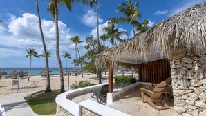 Eine Strandlounge mit Reetdach, Steinmauern und Blick auf den Ozean.