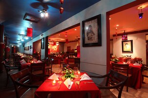 Un restaurante con manteles rojos, sillas de madera y faroles colgantes.