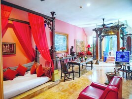 Una habitación amplia con una cama grande, un sofá rojo, una mesa de comedor y un sillón de cuero rojo.