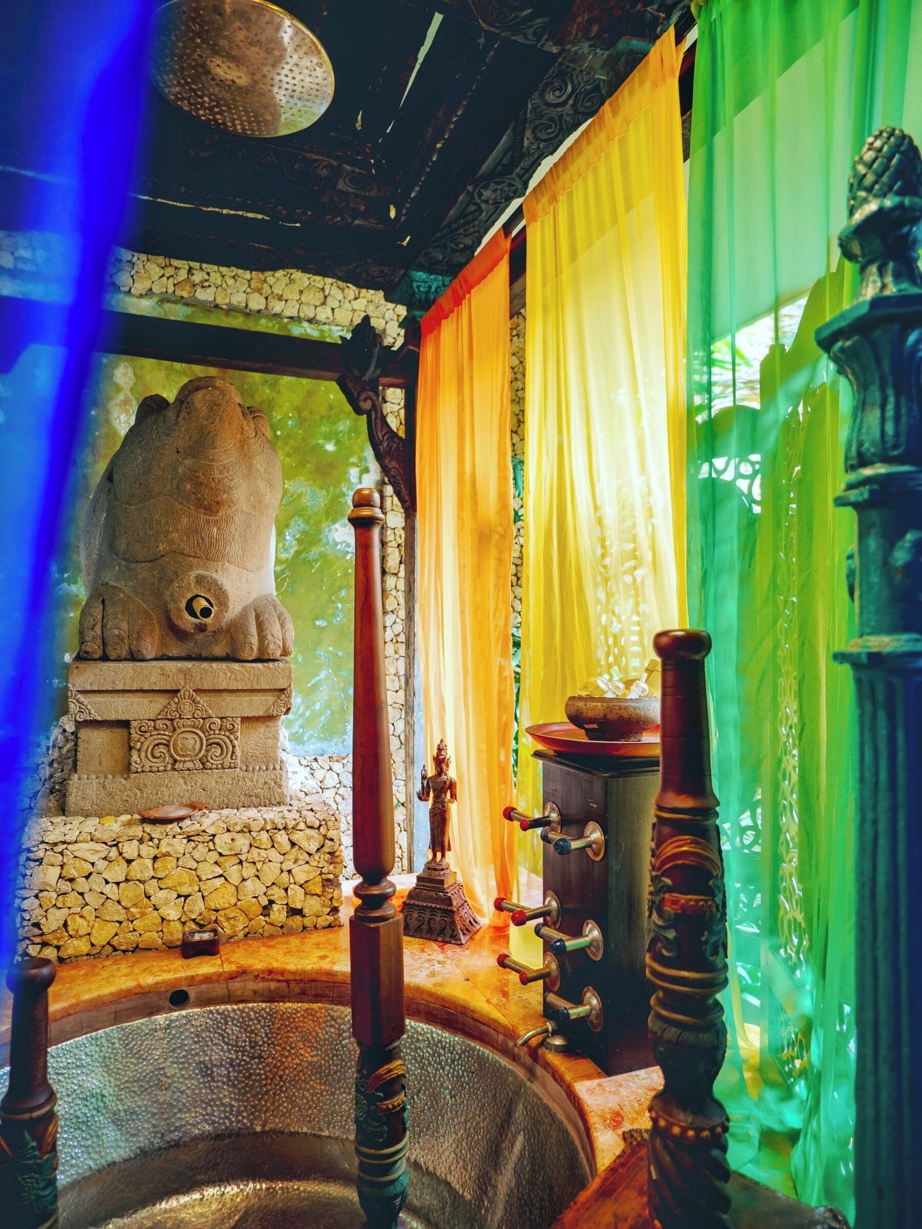 A traditional room with a stone statue, a small Buddha figure, and a water basin with a wooden stand.