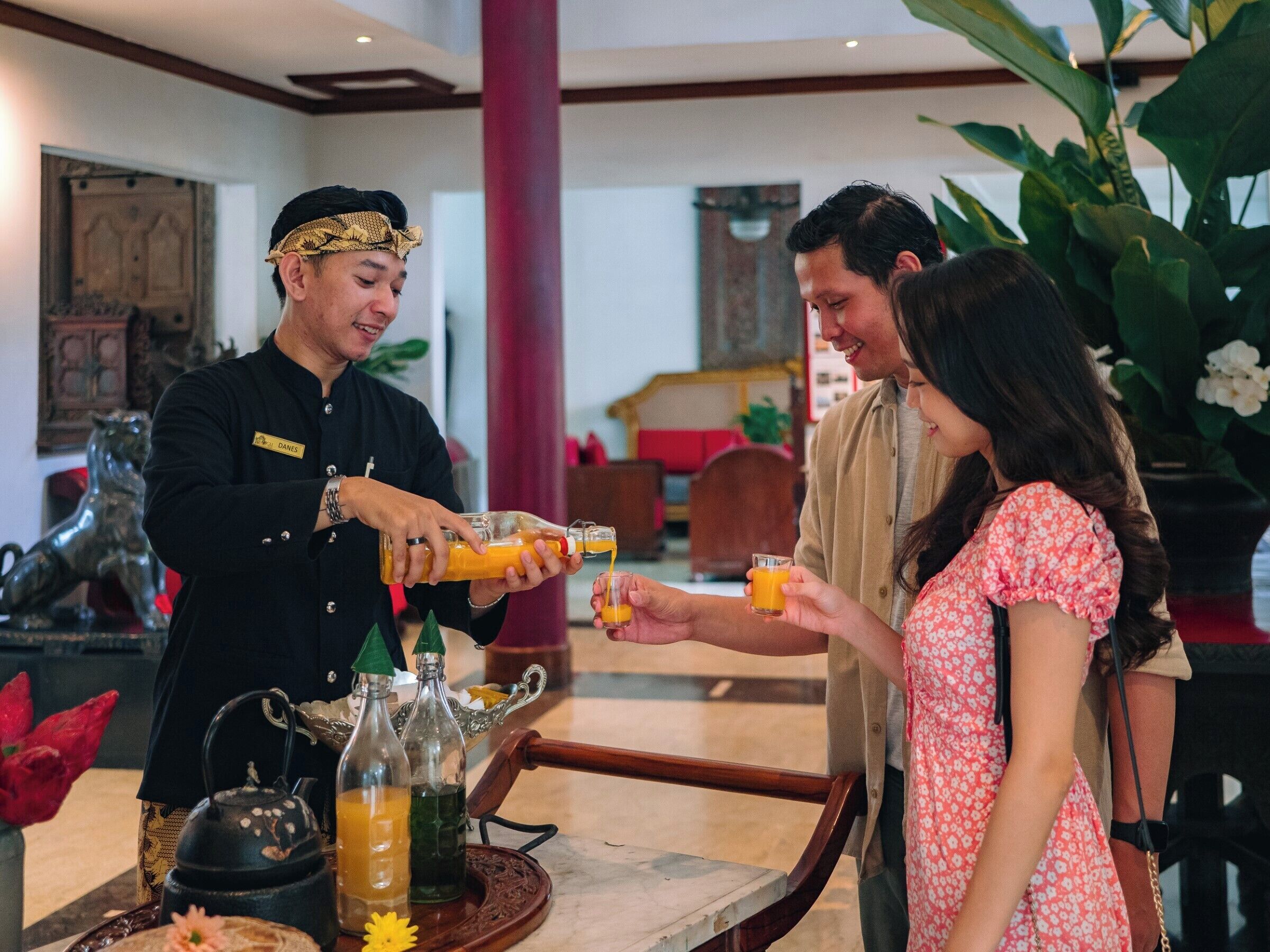 A hotel lobby with a bar area where a bartender is serving drinks to guests.