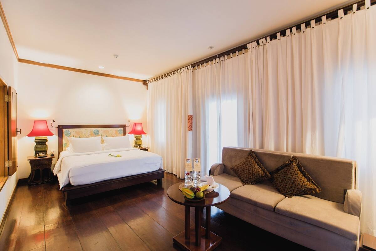 Ein Hotelzimmer mit einem Bett, einer Couch, einem kleinen Tisch mit Früchten und zwei Lampen.