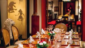 A dining table set with wine glasses, plates, and napkins, with a decorative vase in the center.