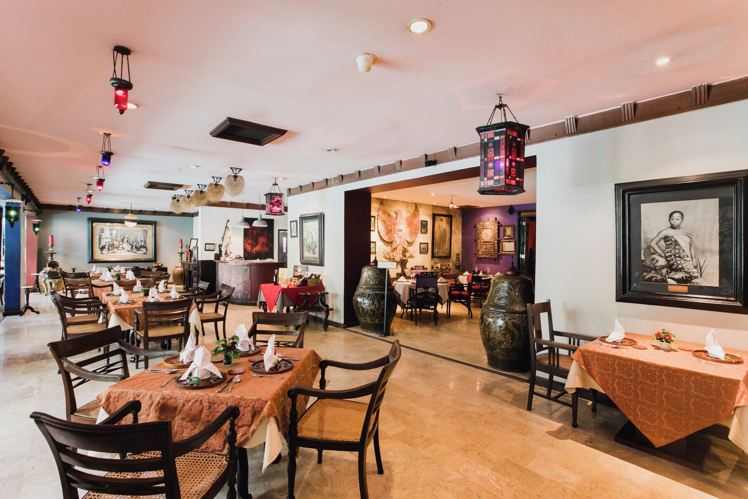 Un restaurante con varias mesas, sillas y faroles colgantes.