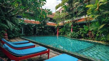 A pool area with lounge chairs and lush tropical plants.