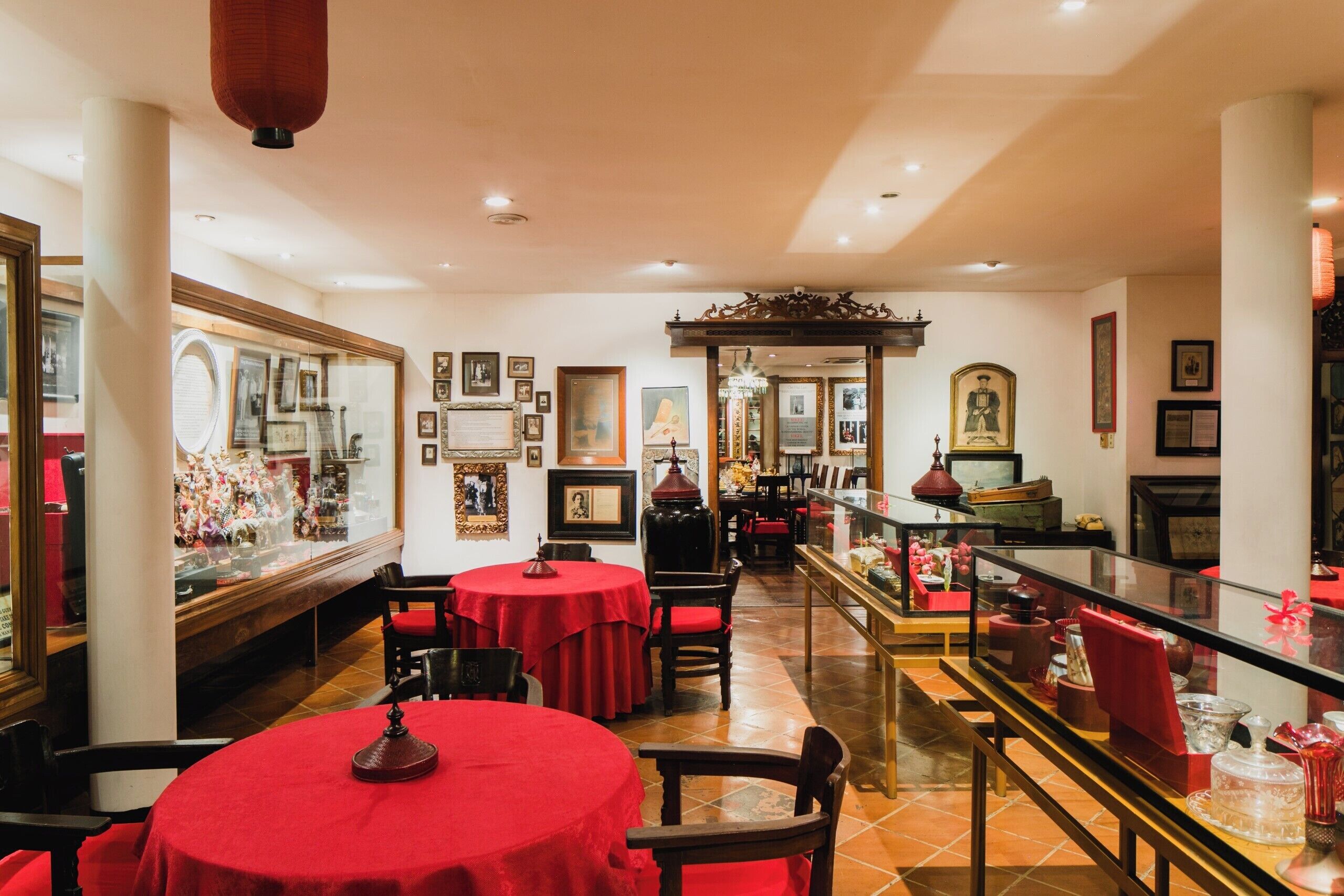 Un restaurant avec des nappes rouges, des chaises en bois et une vitrine.