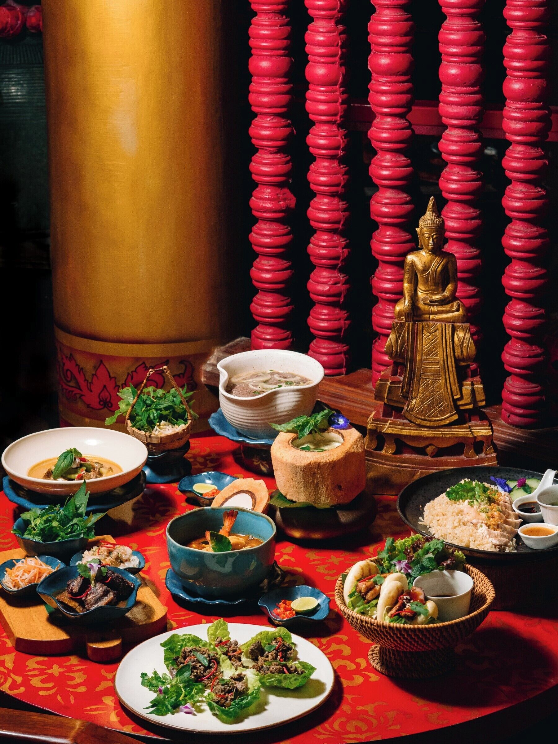 Una mesa con diversos platos, una estatua de Buda y decoraciones tradicionales.