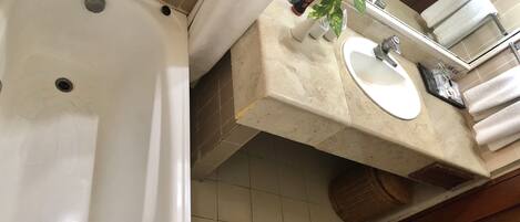 A bathroom with a bathtub, sink, and a mirror above the sink.