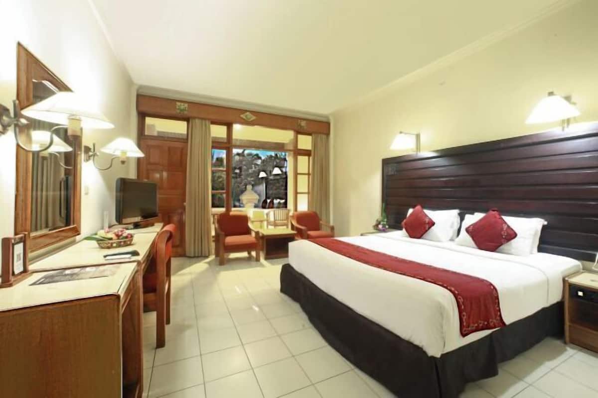 A hotel room with a bed, a desk, a chair, a television, and a view of the outside.