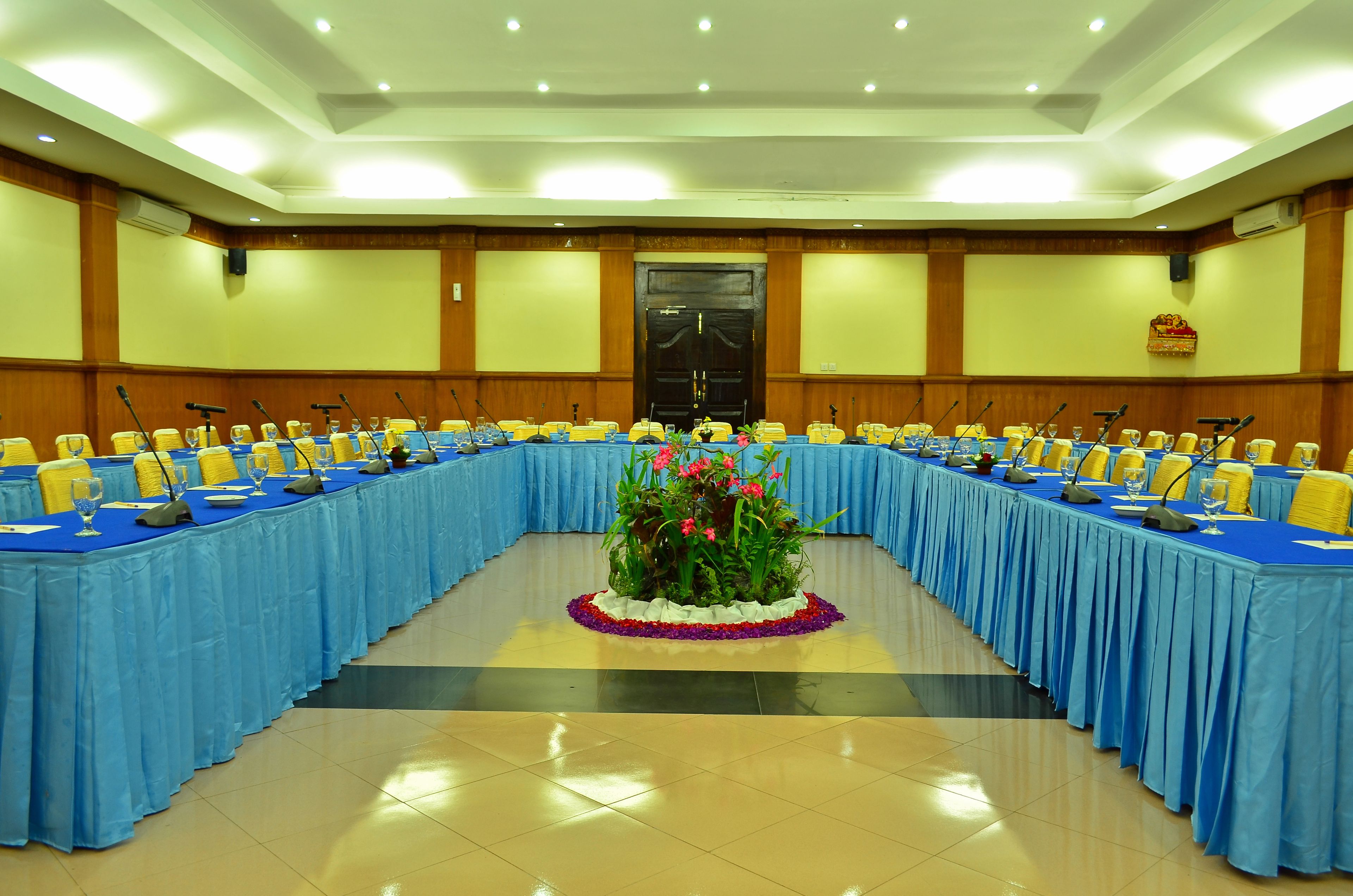 A conference room with a long table, microphones, and chairs.