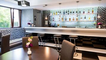 Un espace bar avec un sol à carreaux, des tabourets de bar, un comptoir et une variété de bouteilles exposées sur des étagères.