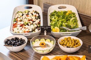 Fresh seasonal salad and a variety of vegetables are served on a table.