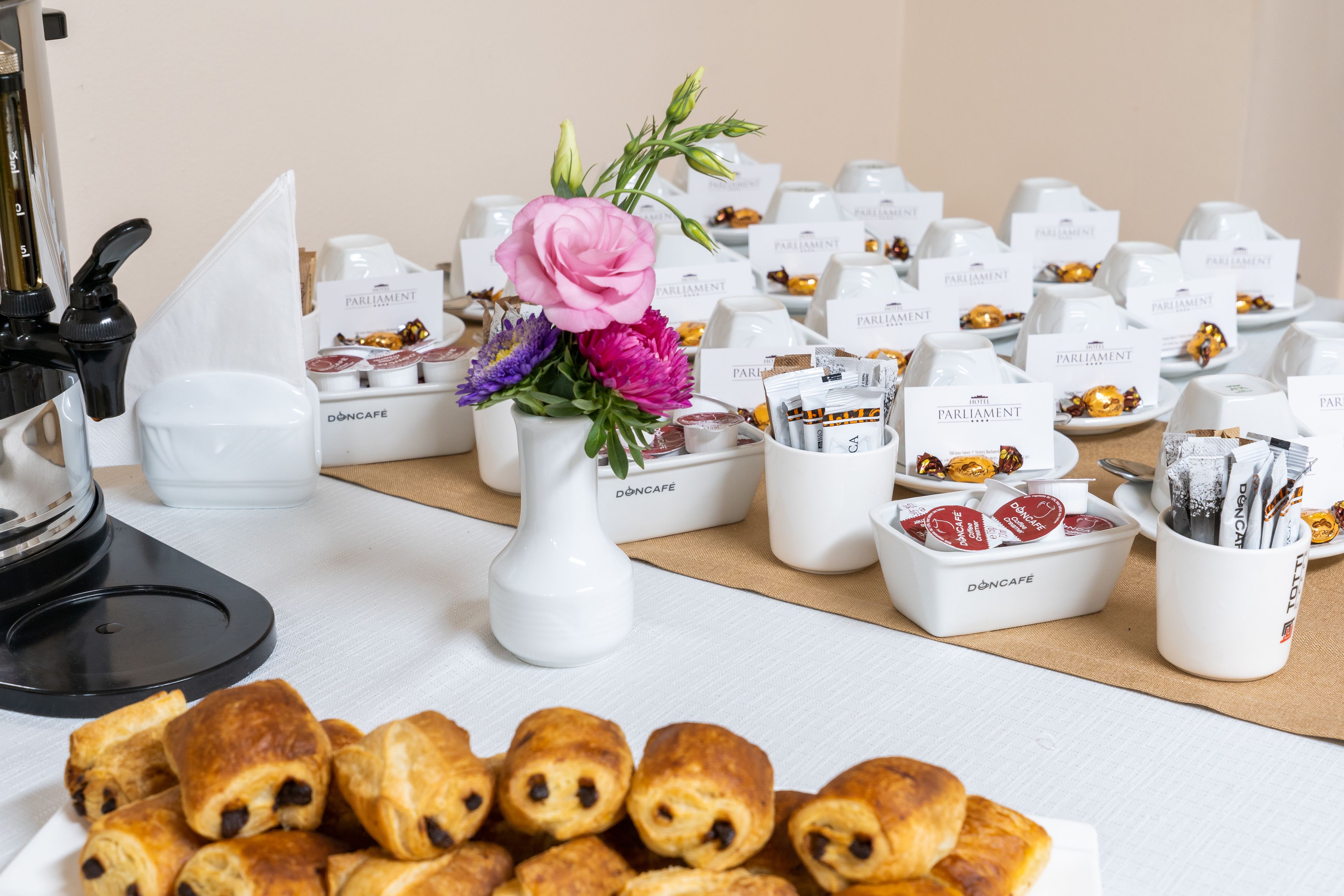 Un tavolo con pasticcini, un vaso di fiori e contenitori etichettati con cibo e bevande.