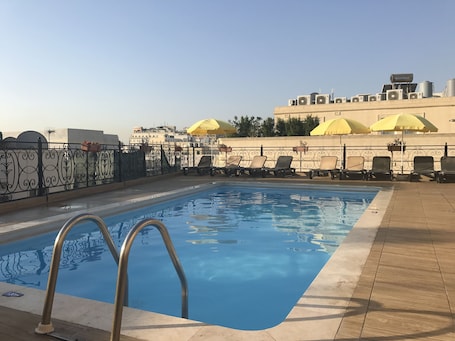 Una piscina al aire libre, sombrillas, sillones reclinables de piscina