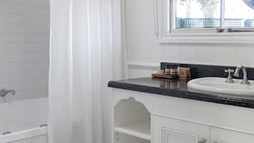 Un baño con una bañera blanca, un lavamanos blanco y una ventana que ofrece vistas a árboles.