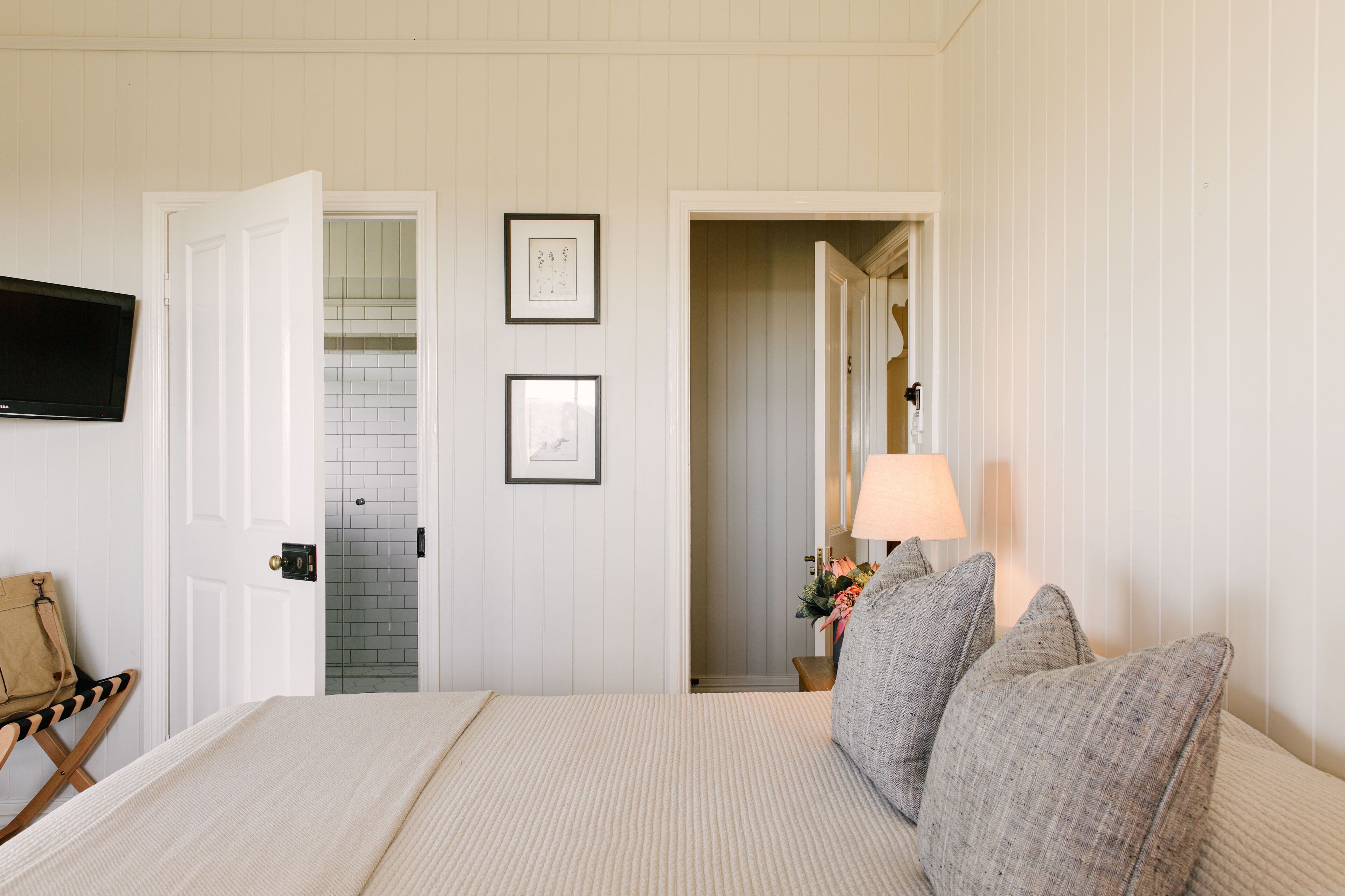 A hotel room with a bed, a television mounted on the wall, and a door leading to a bathroom.
