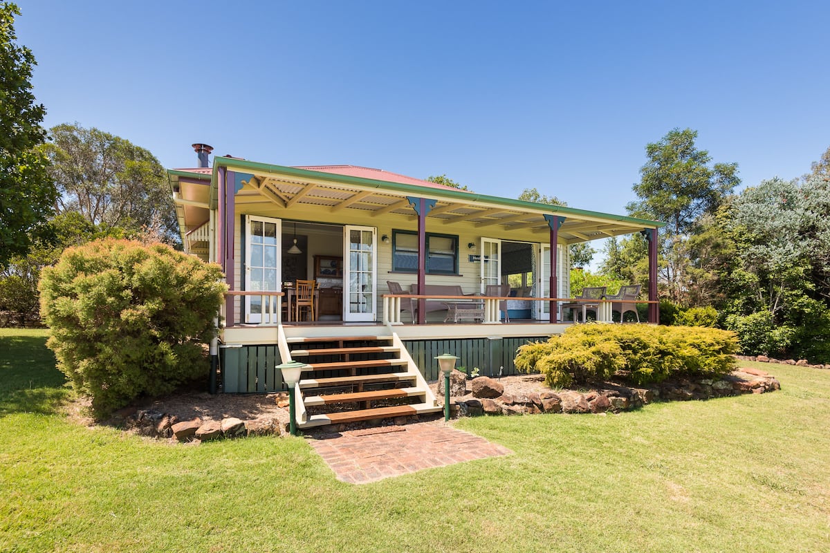 A two-story house with a covered porch, a staircase leading to the entrance, and a well-maintained lawn.