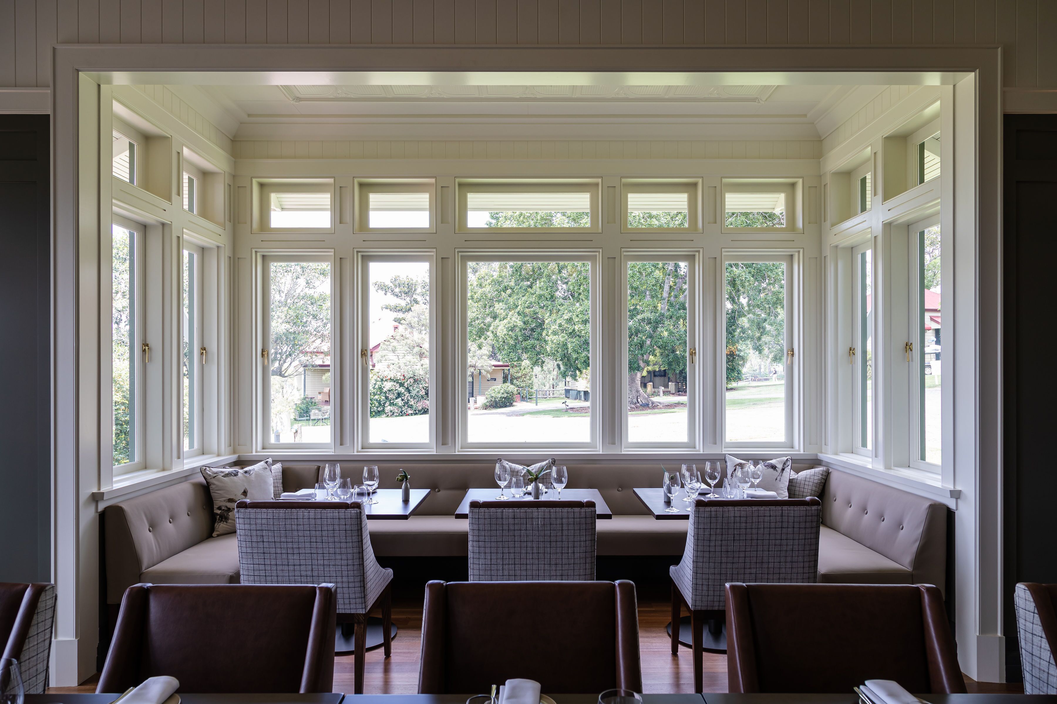 A dining area with a view of the outdoors, featuring a long table with chairs and a bench seating area.