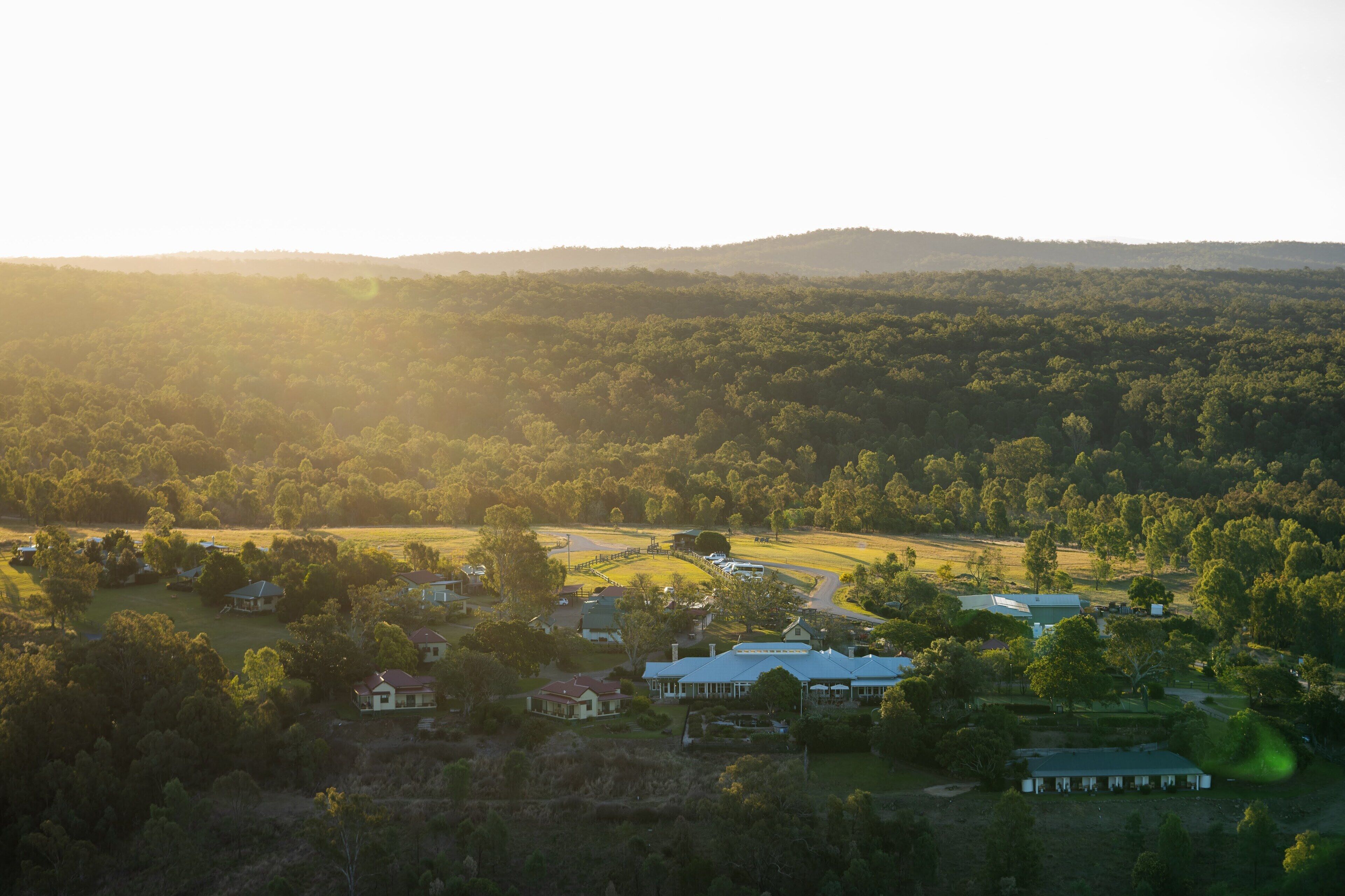 An aerial view of a rural area with houses, roads, and a hilly landscape.