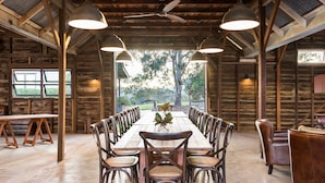 A rustic dining area with a long wooden table, multiple chairs, and pendant lights. - Spicers Hidden Vale (Grandchester)