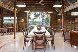 A rustic dining area with a long wooden table, multiple chairs, and pendant lights.