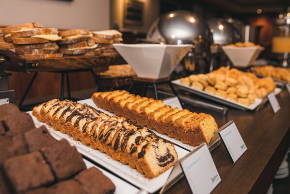 A variety of baked goods displayed on trays at a bakery counter.