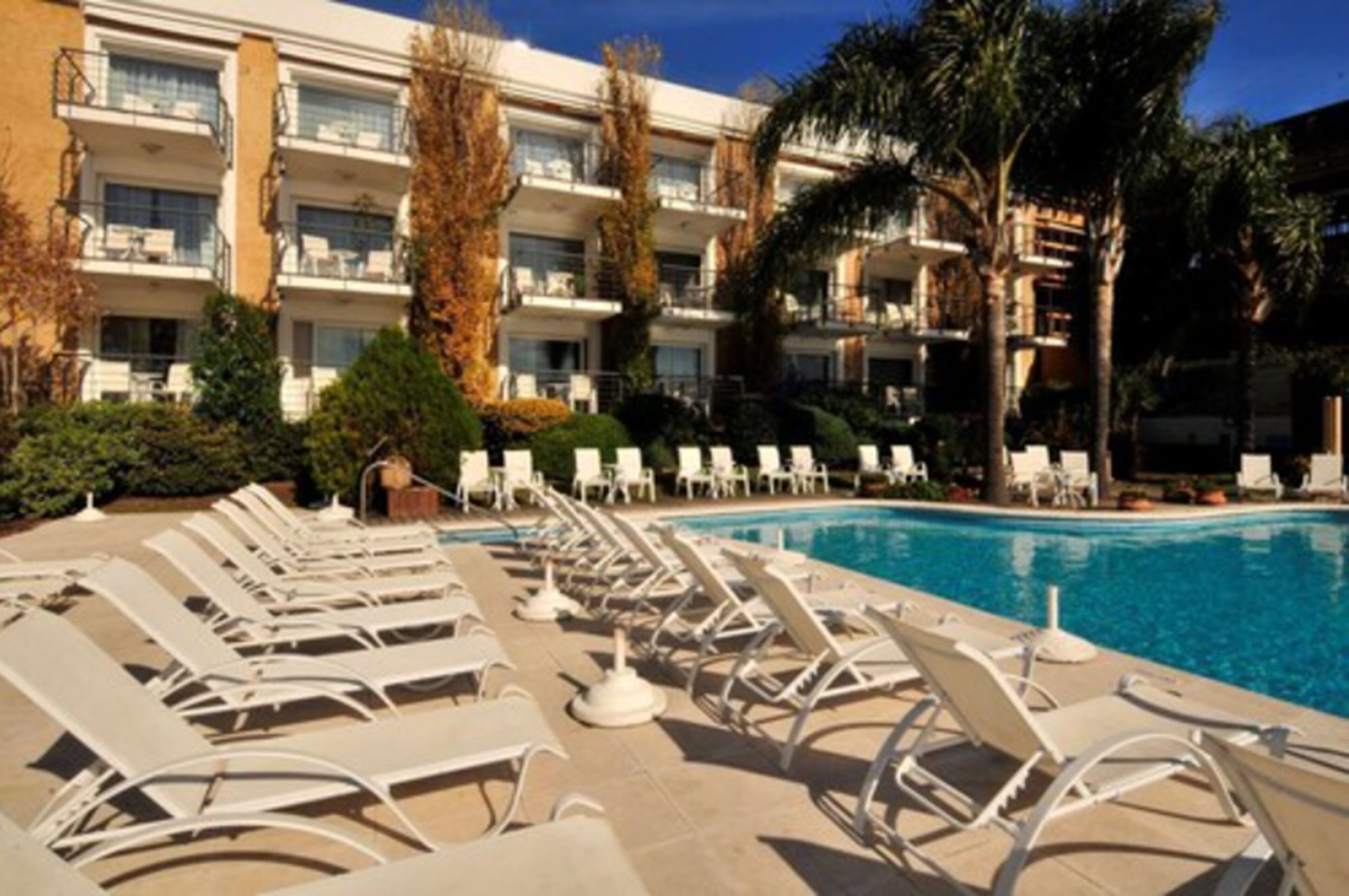 Ett hotell med ett poolområde som har solstolar och en klarblå pool.