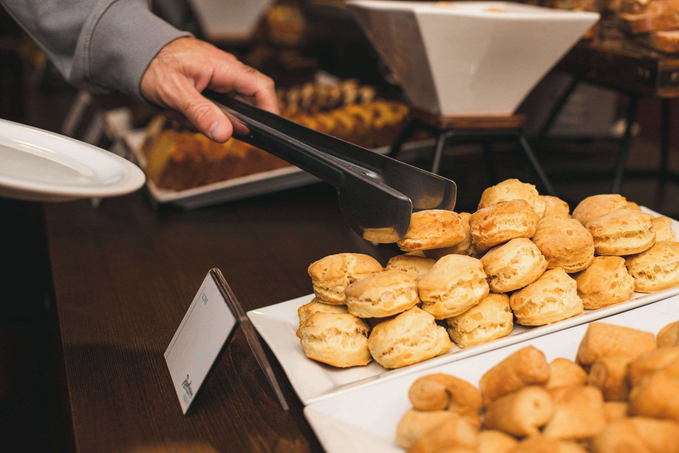 Una mesa de buffet con diversas opciones de panadería, incluyendo galletas y pasteles.