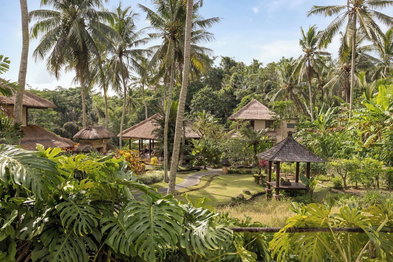 Um resort tropical com palafitas de telhado de palha, vegetação exuberante e céu claro.