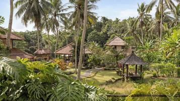 Um resort tropical com palafitas de telhado de palha, vegetação exuberante e céu claro.