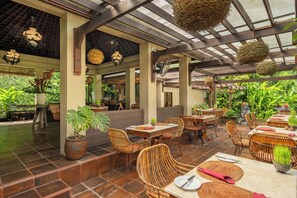 An outdoor restaurant with wicker furniture, potted plants, and hanging lanterns. - Villa Semana Resort & Spa (Ubud)