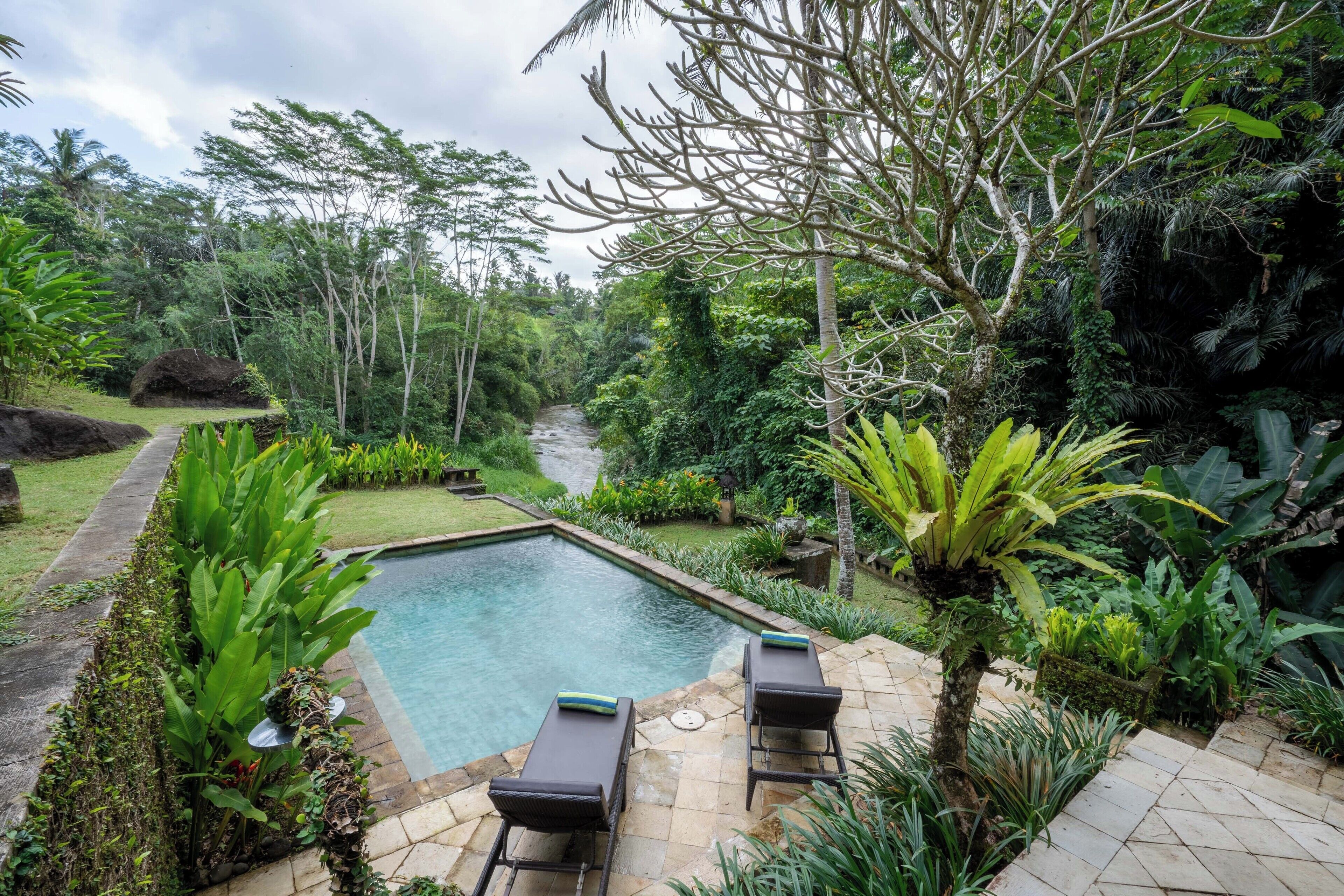 A pool area with lounge chairs and a stone pathway.