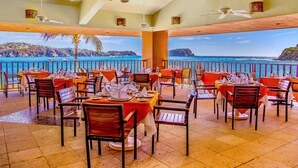 Un restaurante con mesas dispuestas para comer, con vistas a un paisaje costero.