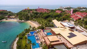 Vista aérea de un resort con piscina, canchas de tenis y acceso a la playa.