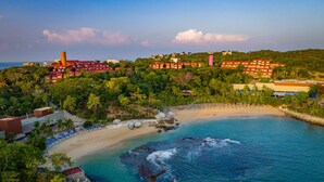 Un resort costero con villas frente a la playa, una playa de arena y un litoral rocoso.