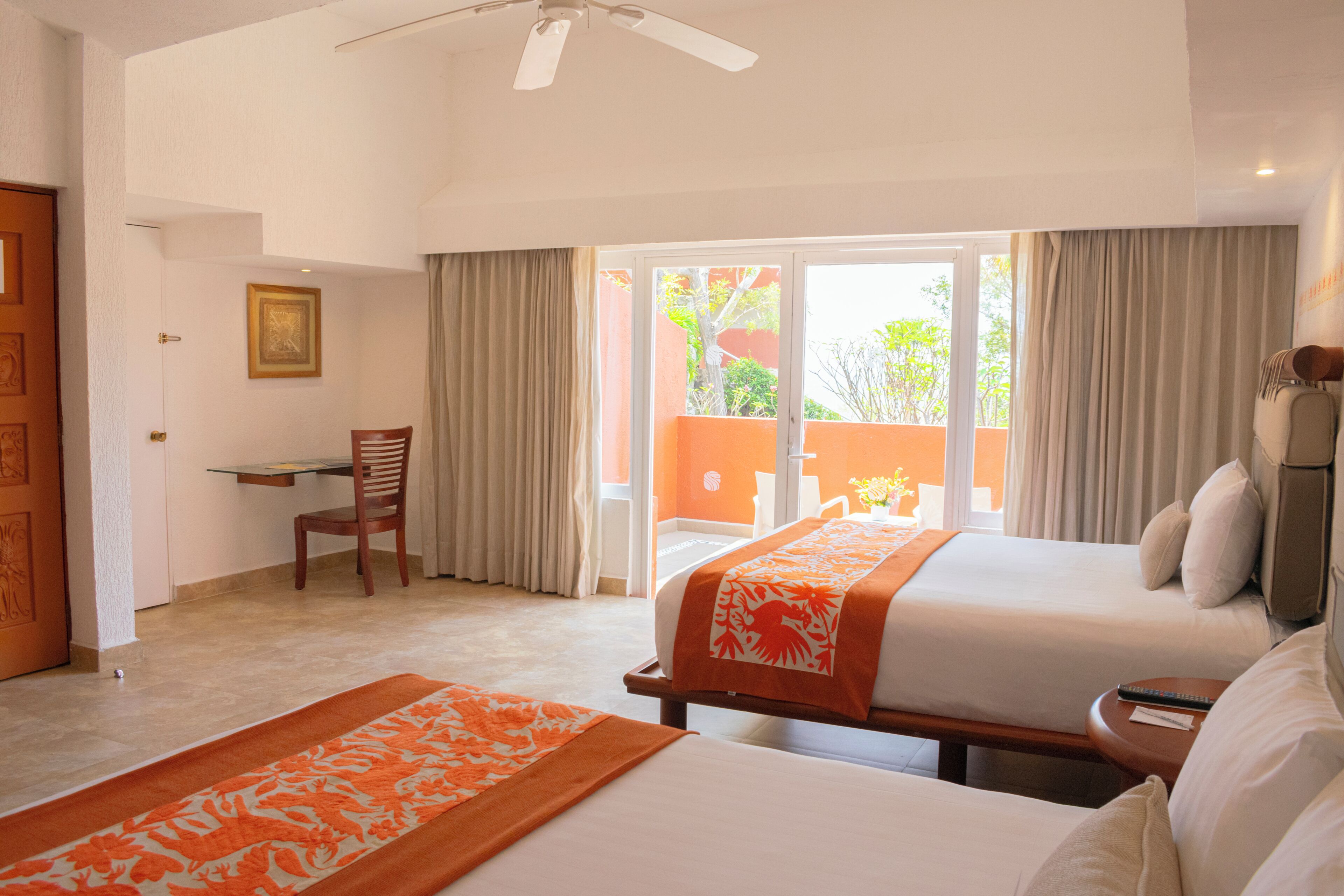 A hotel room with two beds, a desk, a chair, and a view of the outside.