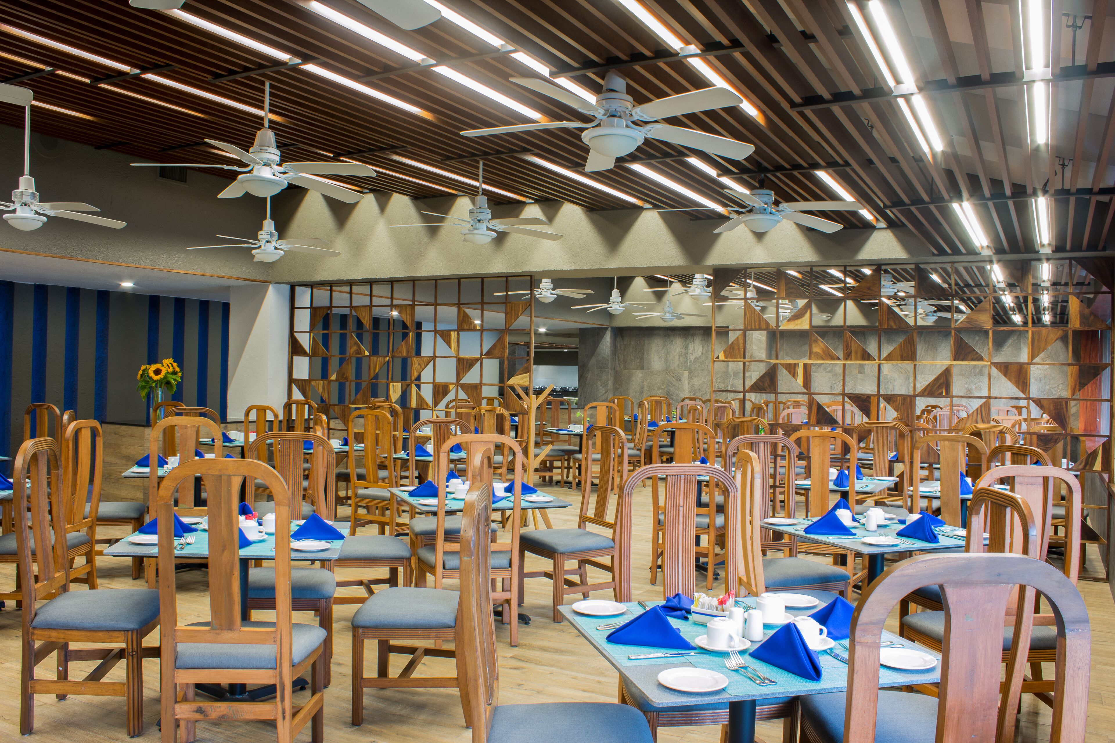 A restaurant with multiple tables and chairs, ceiling fans, and a wooden ceiling.