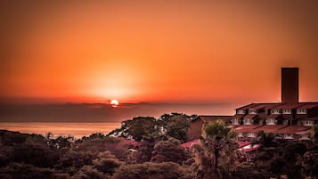 A coastal sunset view with a prominent tower and a multi-story building with balconies.