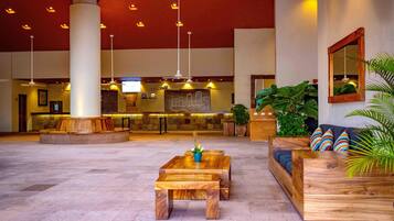 A spacious lobby with a reception desk, wooden seating, and ceiling fans.