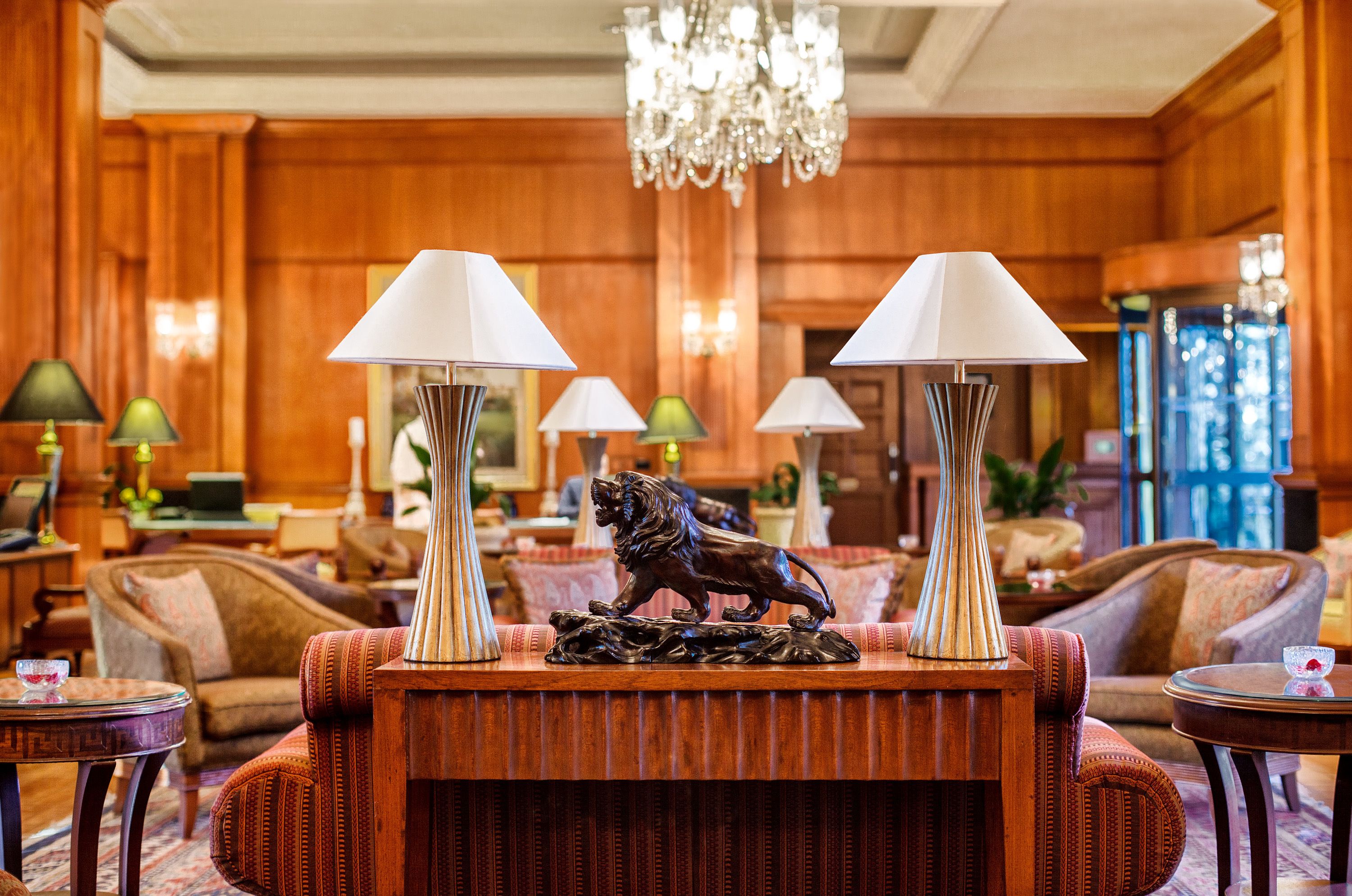 A lobby with wooden paneling, a chandelier, and multiple lamps.