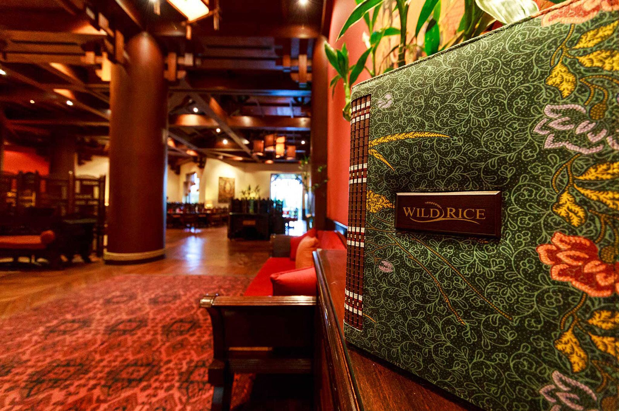 A lobby with a patterned wall, a sign reading "WILD RICE", and seating areas.