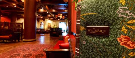 A lobby with a patterned wall, a sign reading "WILD RICE", and seating areas.