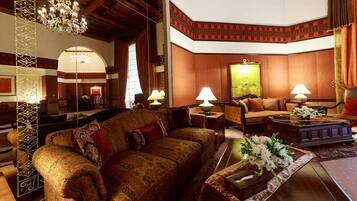 A spacious living room with a large sofa, a coffee table with flowers, and a painting on the wall.