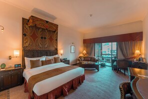 A hotel room with a large bed, a sofa, a desk, and a view of the city. - Islamabad Serena Hotel (Islamabad)