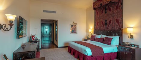 Une chambre d’hôtel avec un grand lit, un bureau, une chaise, une table de chevet, une lampe et un téléphone.