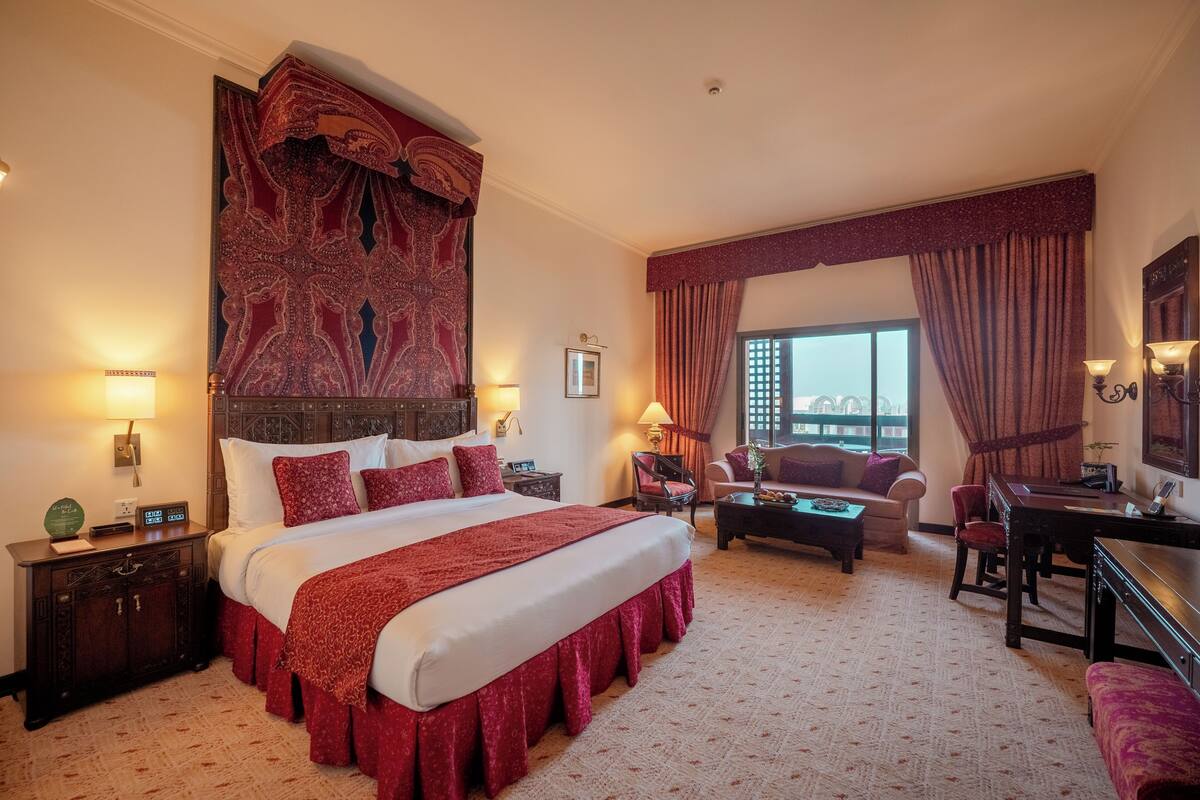 Habitación de hotel con una cama grande, un escritorio, una silla, un sofá y vistas a la ciudad.
