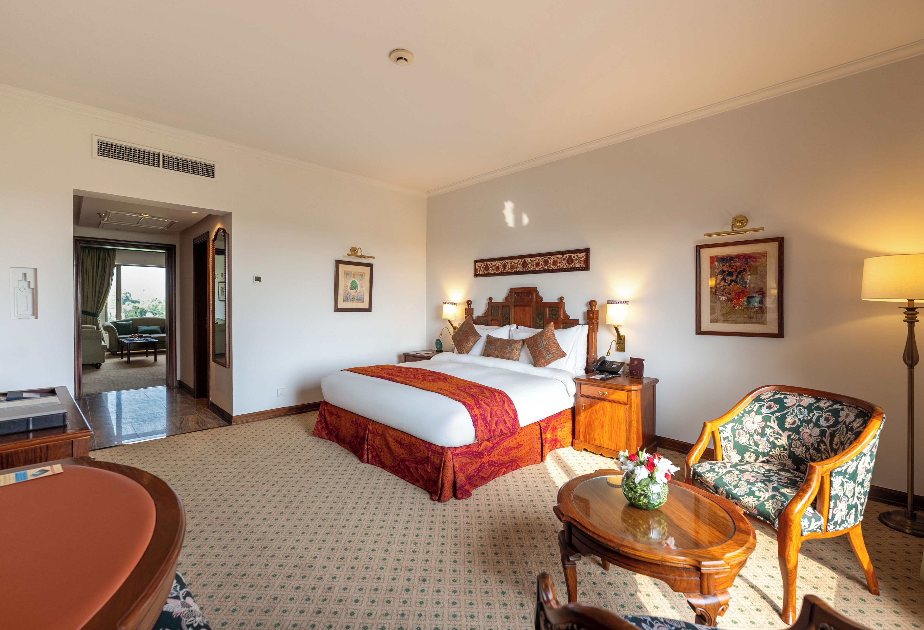 A hotel room with a bed, a desk, a chair, a lamp, and a picture on the wall.